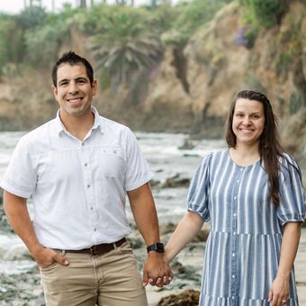 A man and a woman are holding hands on the beach.