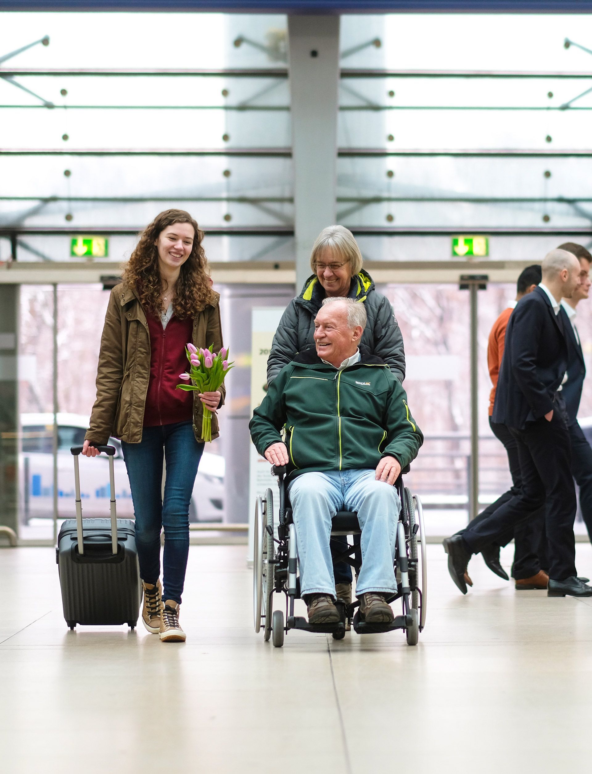 Ein Mann im Rollstuhl wird von zwei Frauen geschoben