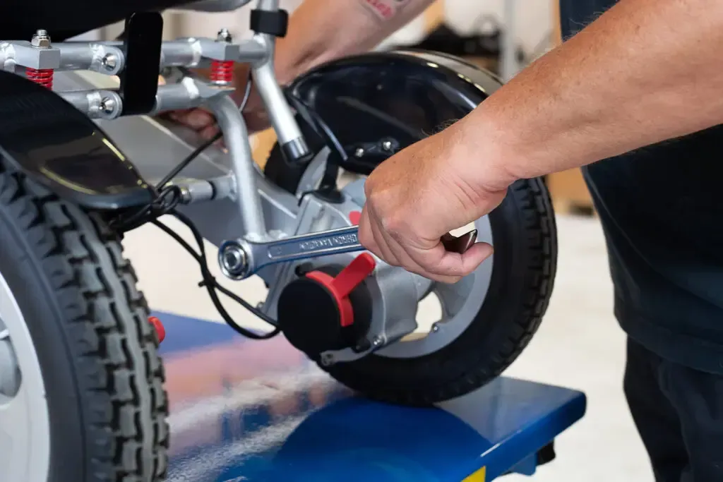 Ein Mann arbeitet mit einem Schraubenschlüssel an einem Rollstuhl.