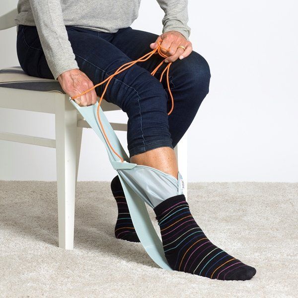 Eine Person sitzt auf einem Stuhl und zieht Socken an