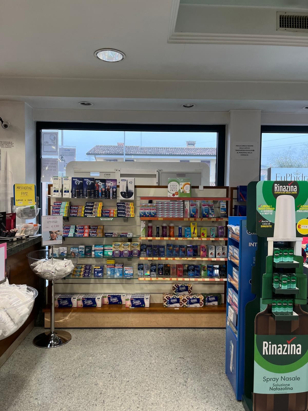 L'interno di una farmacia con espositore per rinazina
