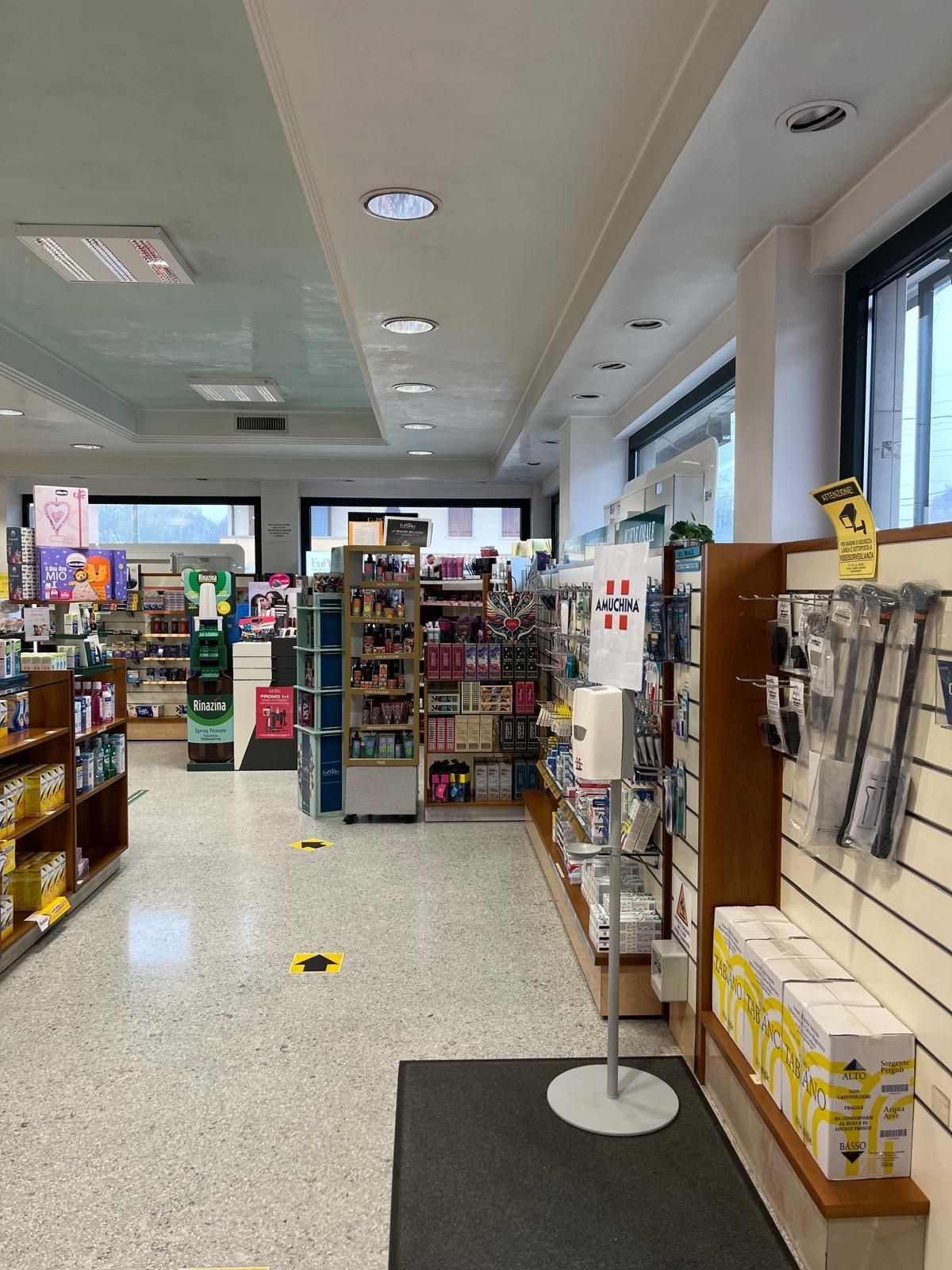L'interno di una farmacia con un distributore di disinfettante per le mani sul pavimento.