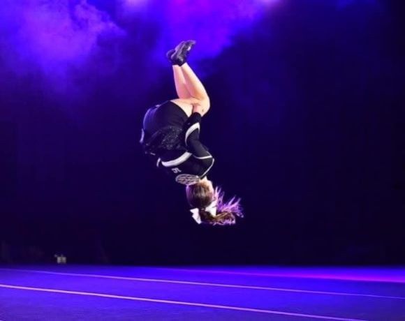 A cheerleader is doing a handstand in the air