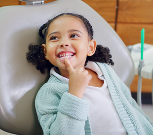 Child receiving a dental exam while a dentist uses tools inside their mouth