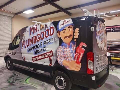 A van with a plumber on it is sitting in a garage.