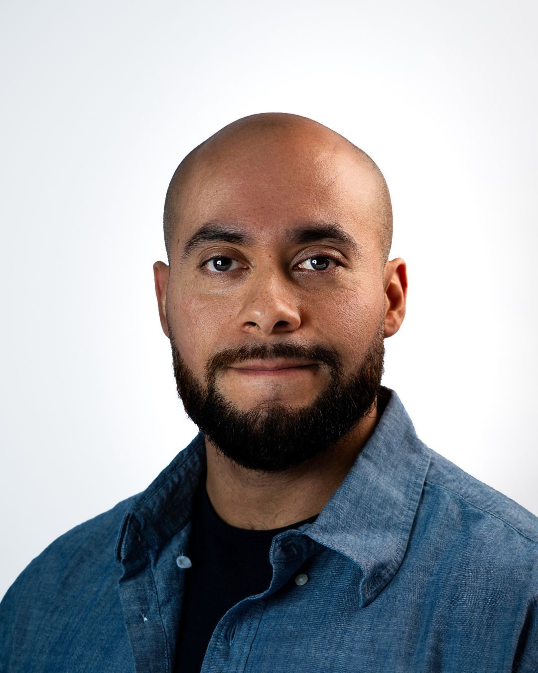 A bald man with a beard is wearing a green shirt.