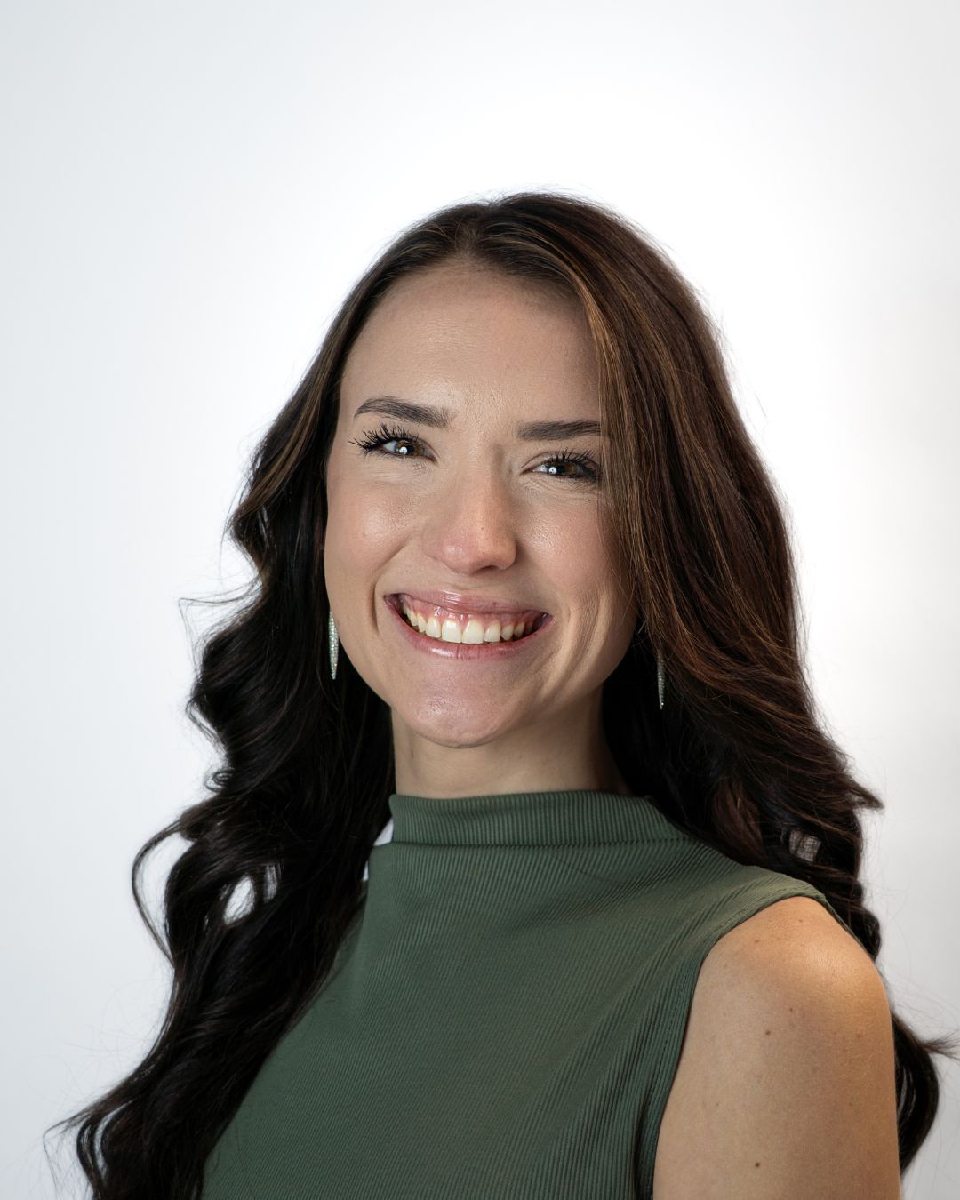 A woman in a grey sweater is smiling for the camera.