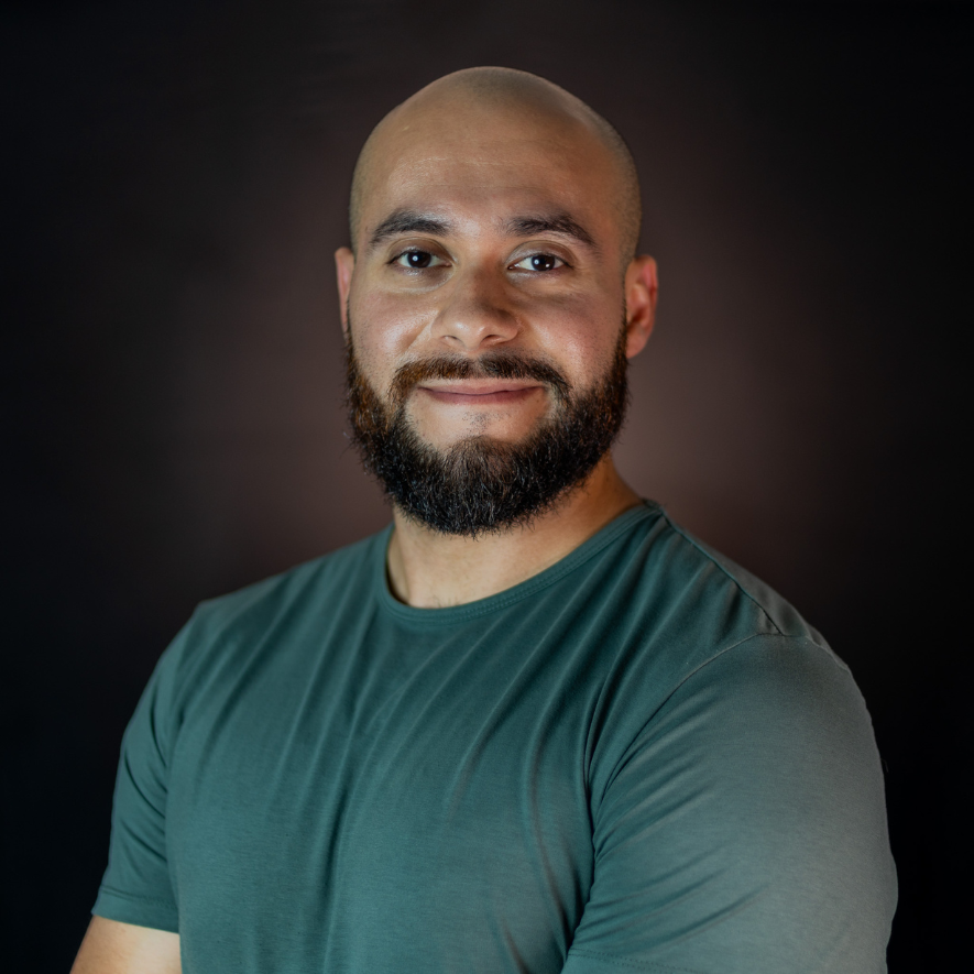 A bald man with a beard is wearing a green shirt.