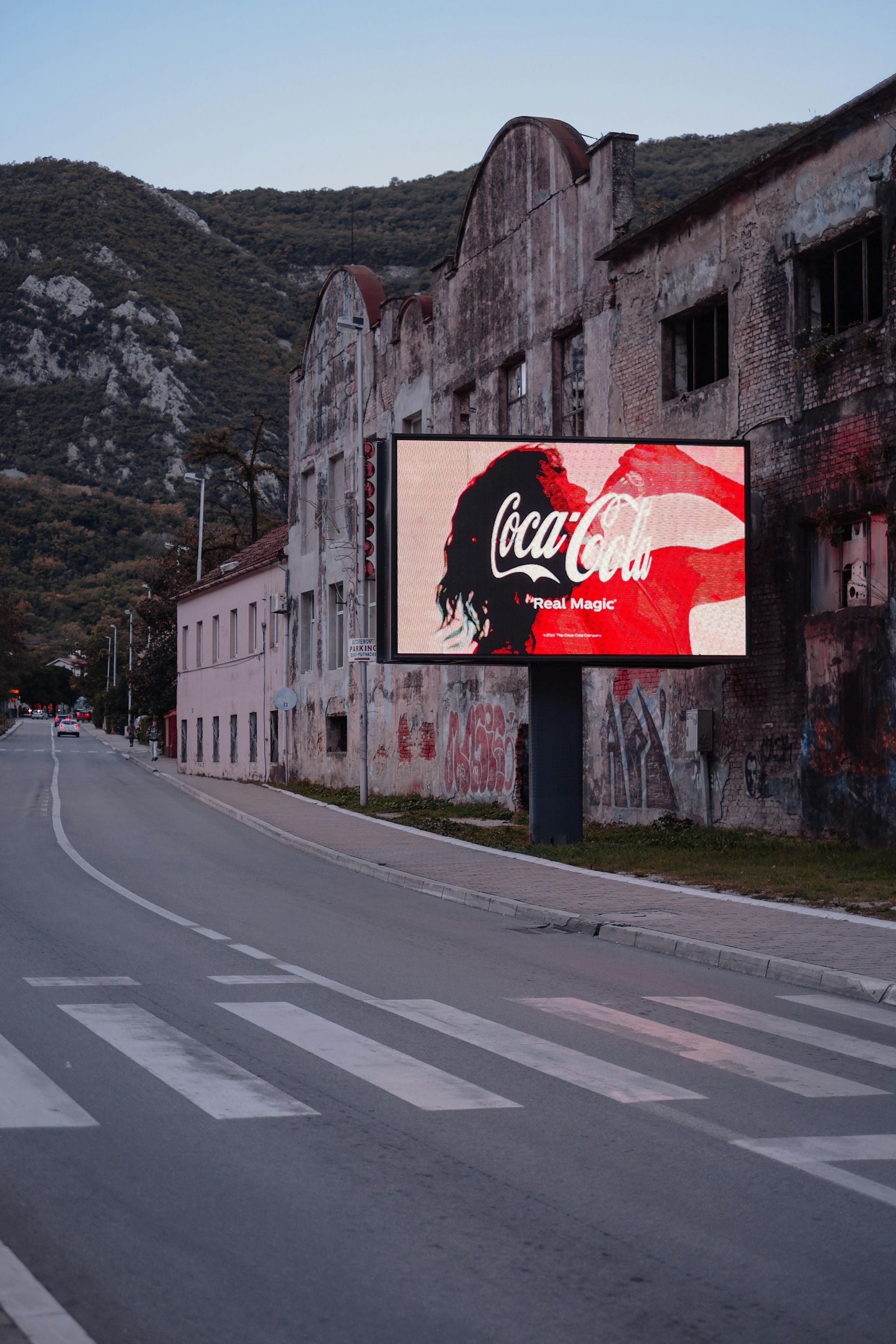 A coca cola billboard is sitting on the side of a road.