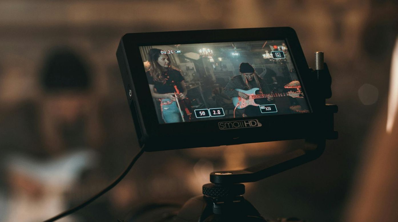 A camera is recording a man playing a guitar on a screen.