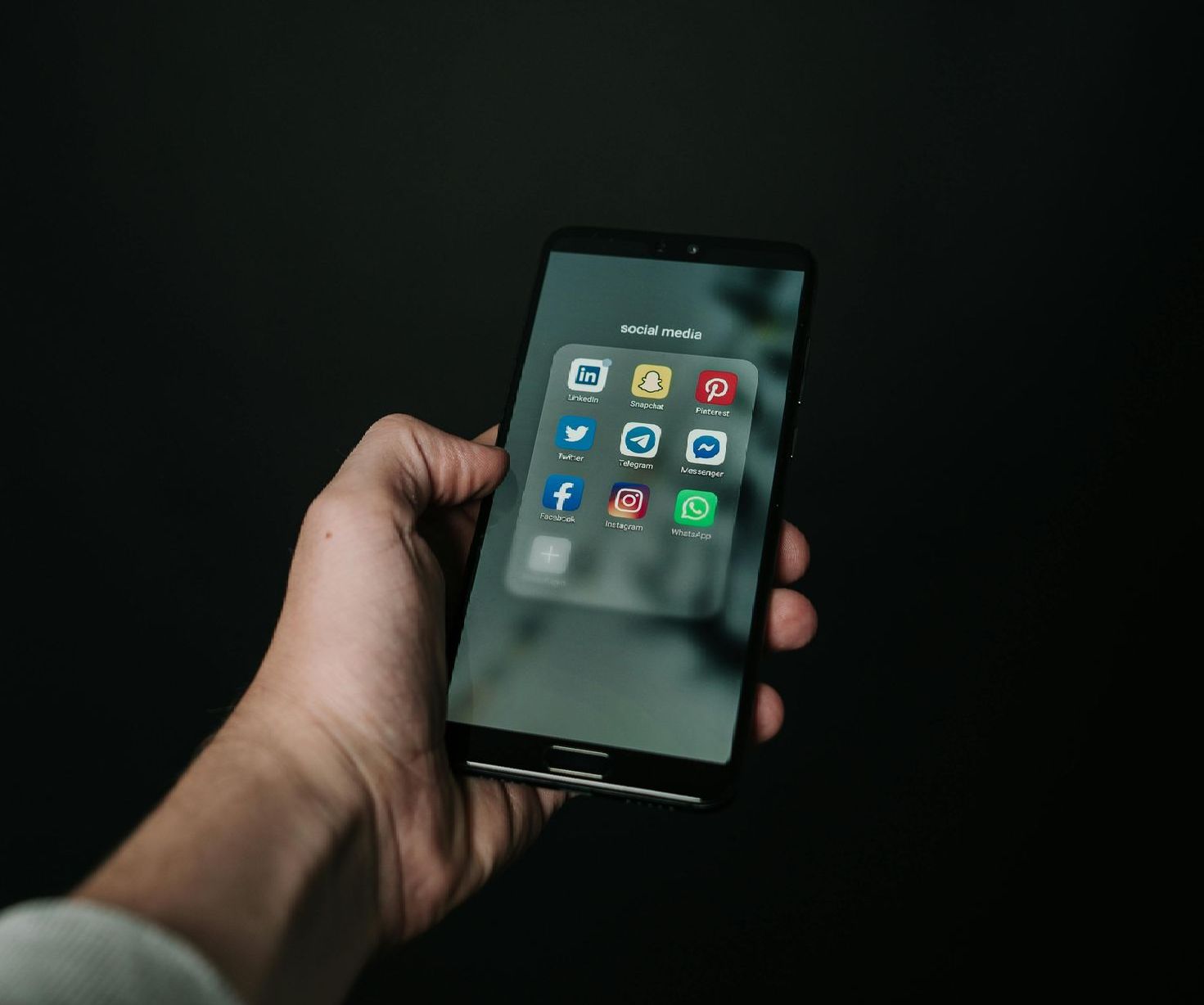A person is holding a cell phone with a bunch of apps on it.