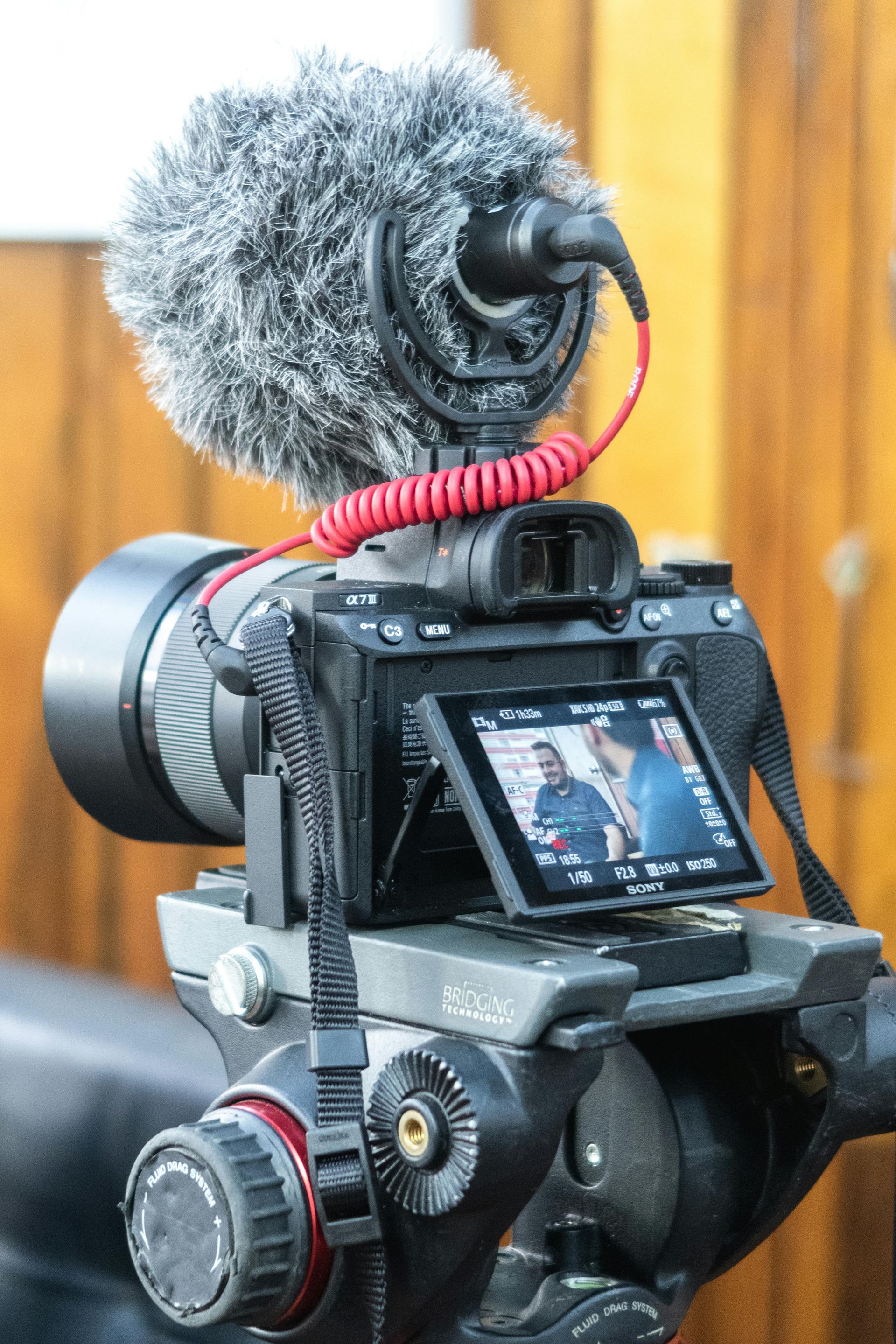 A camera with a microphone attached to it is on a tripod.
