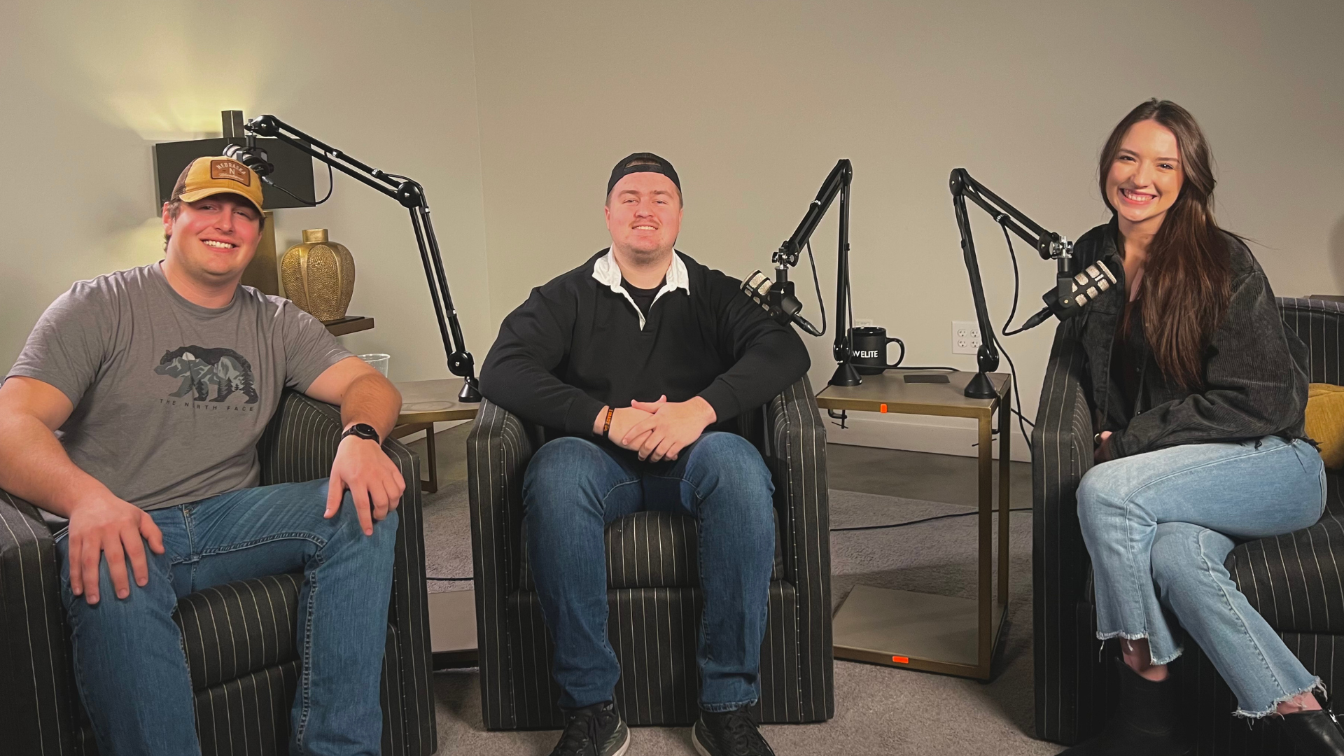 Three people are sitting in chairs in front of a microphone.