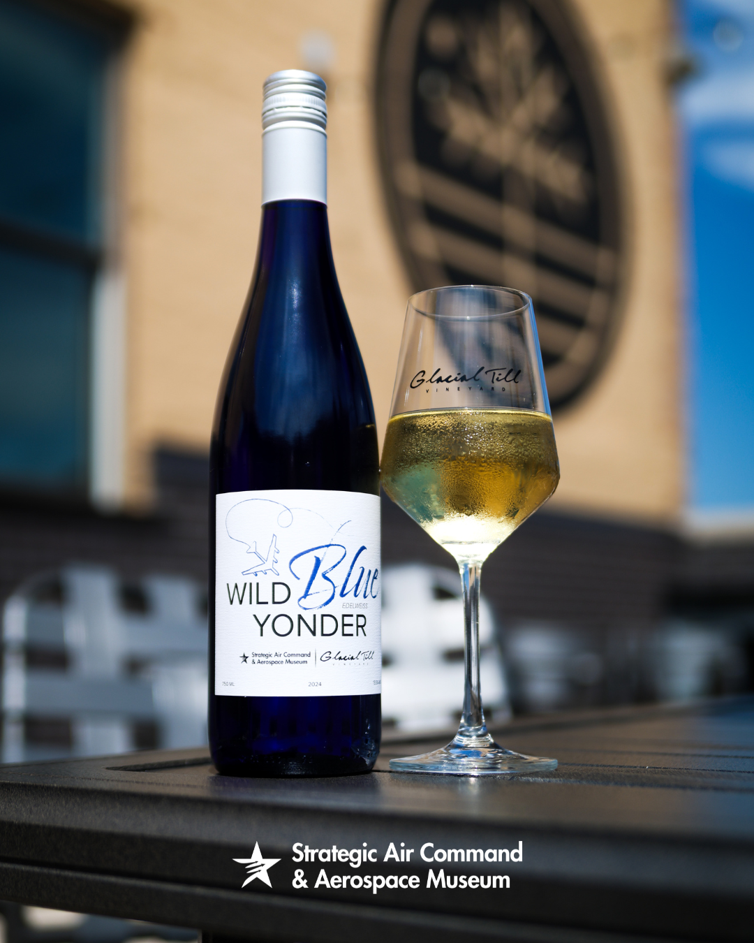 Bottle and glass of white wine on table, with label reading