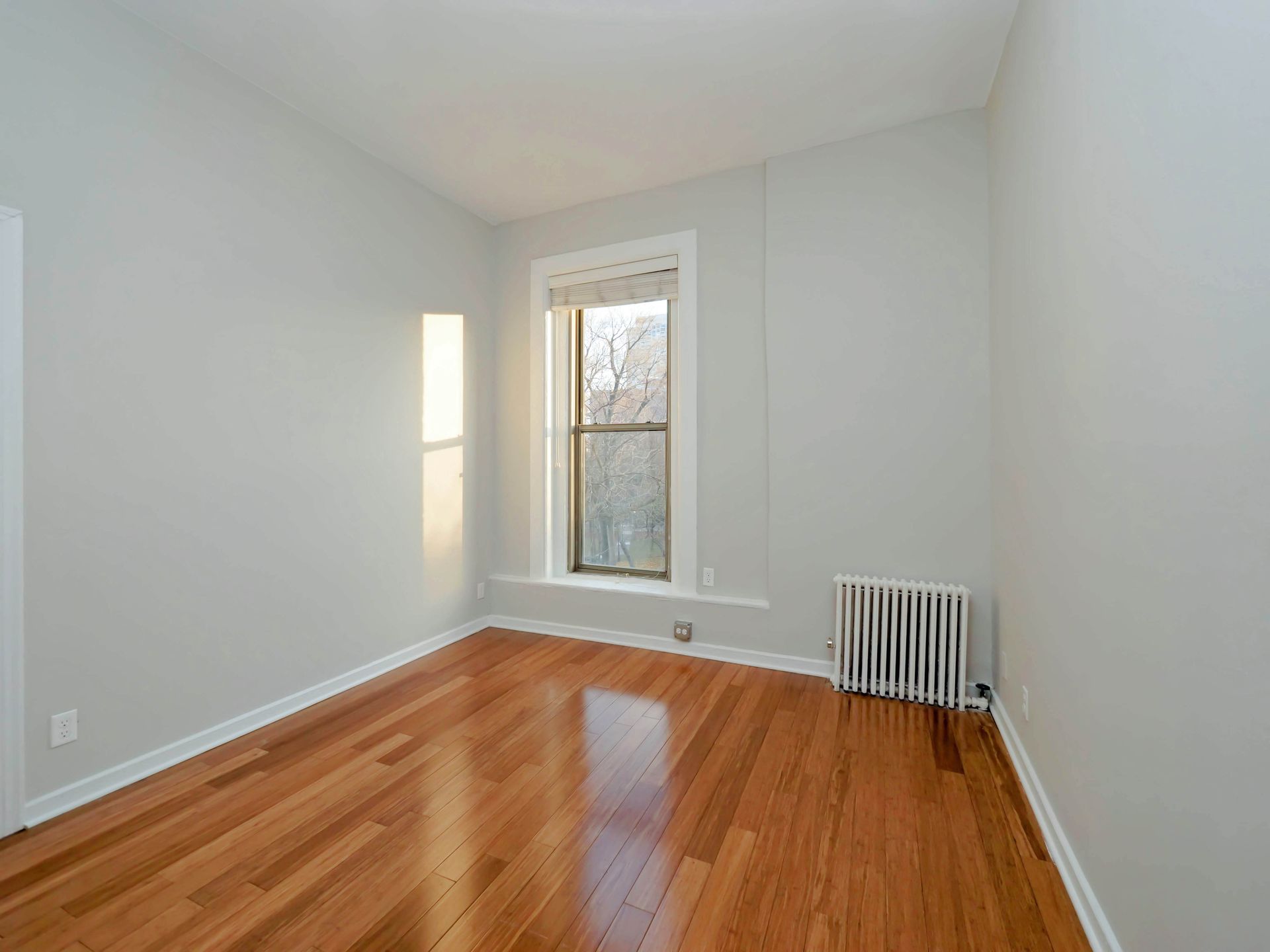 An empty room with hardwood floors and a window at Reside on Clark.