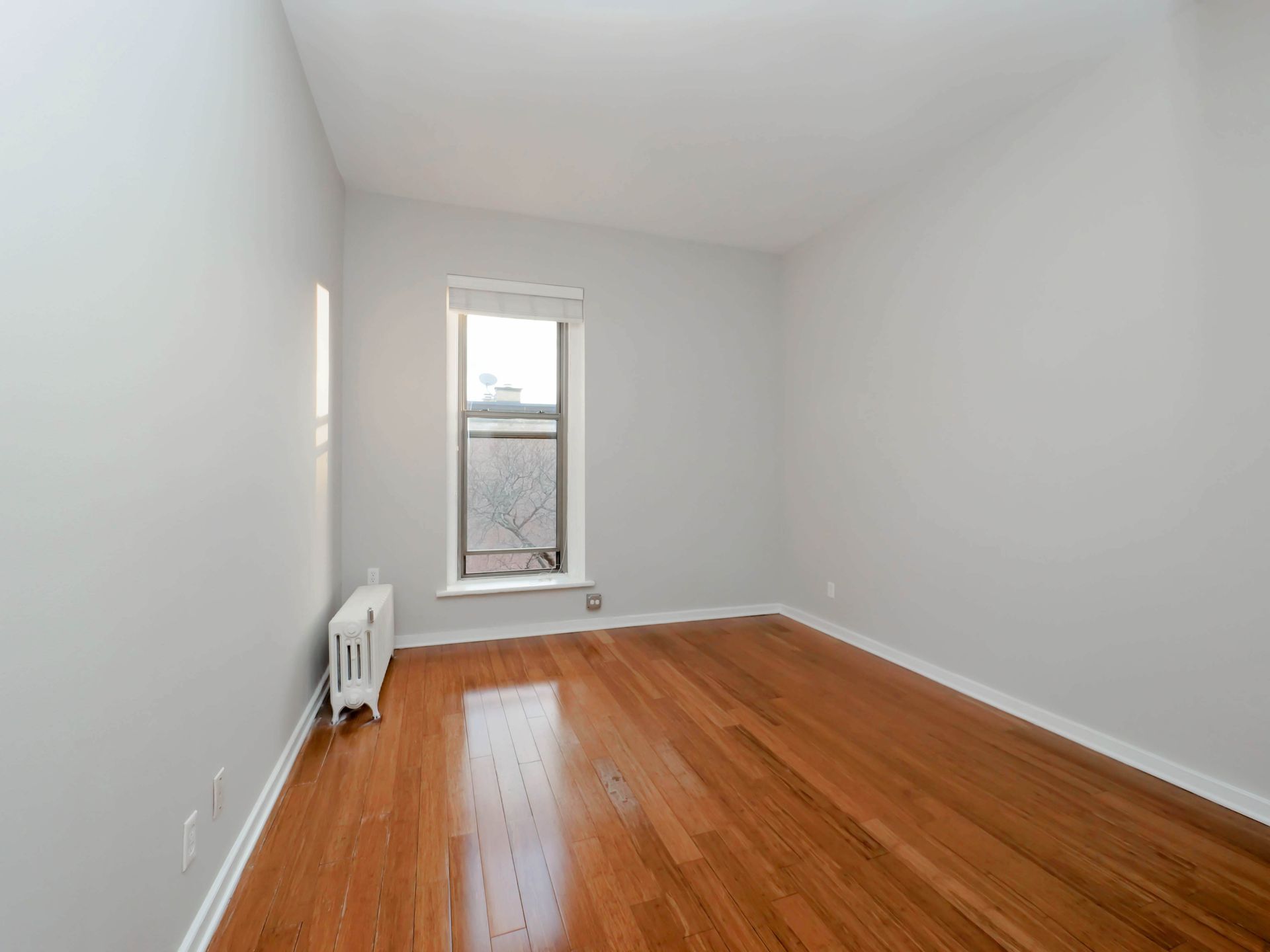 An empty room with hardwood floors and a window at Reside on Clark.