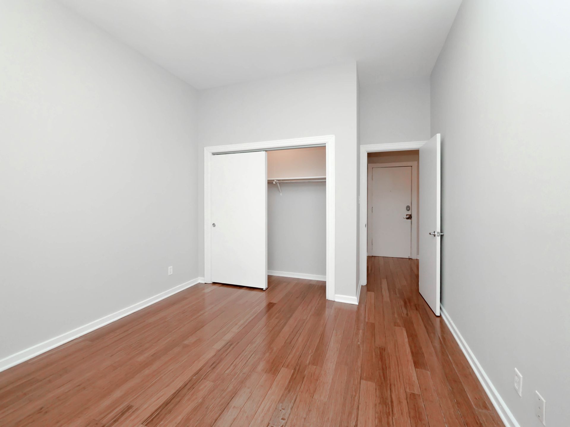 An empty bedroom with hardwood floors and white walls at Reside on Clark.