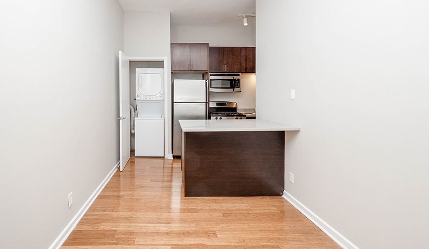 An empty apartment with a kitchen and a refrigerator at Reside on Clark.