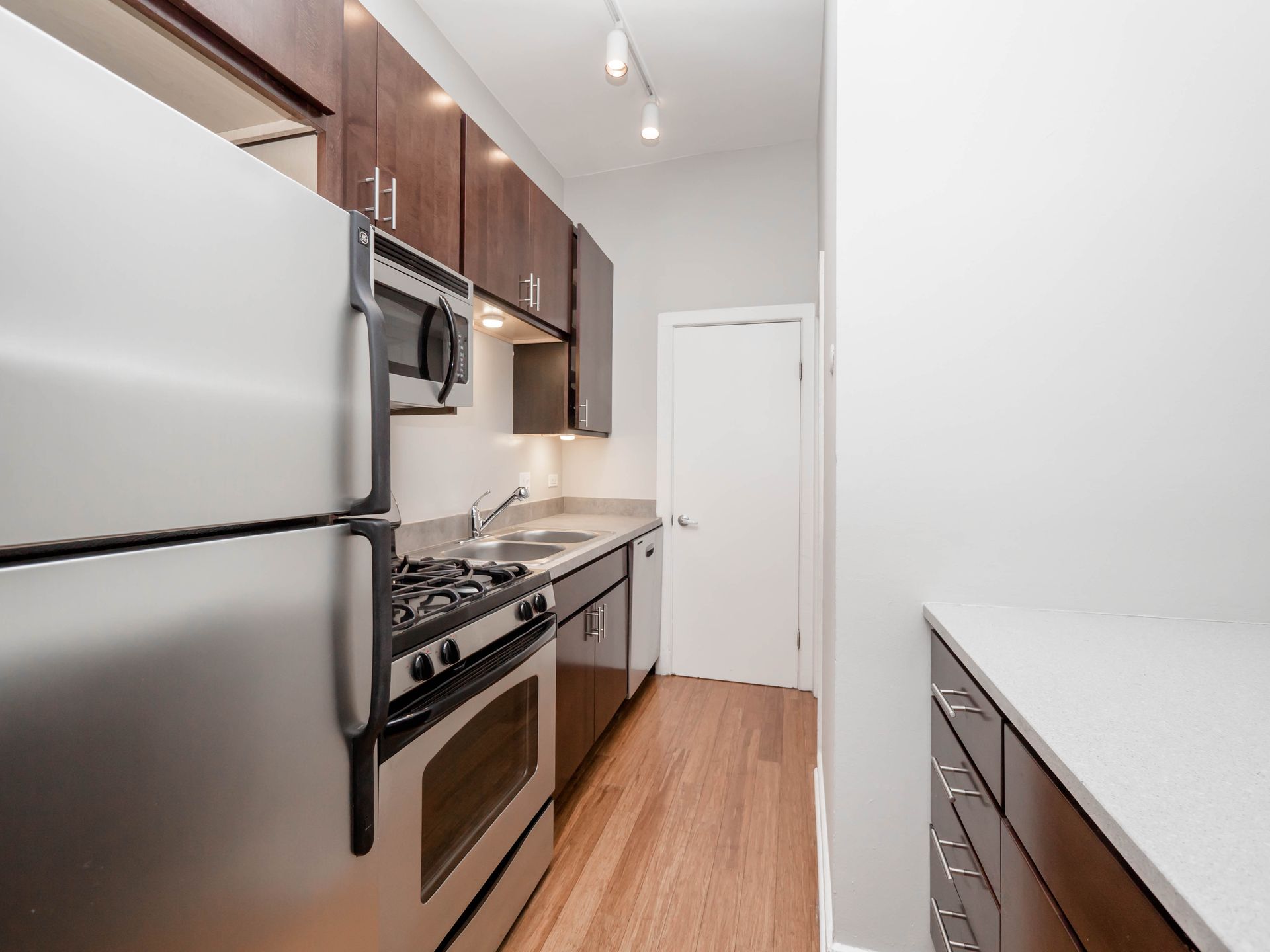 Apartment kitchen with stainless steel appliances and wooden cabinets at Reside on Clark.