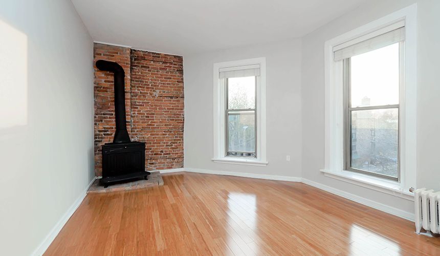 An empty living room with hardwood floors and a fireplace at Reside on Clark.