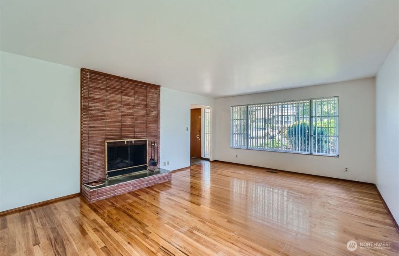 An empty living room with hardwood floors and a fireplace