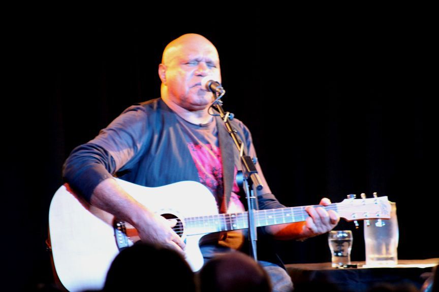 A man singing into a microphone while playing a guitar