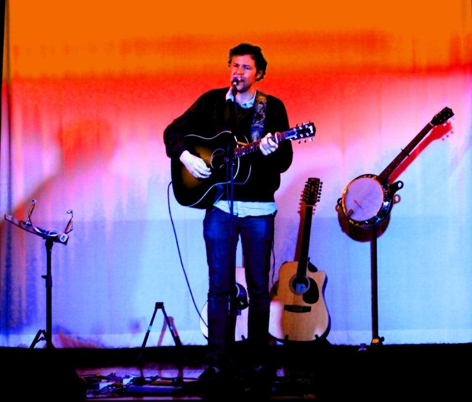 A man singing into a microphone while playing a guitar