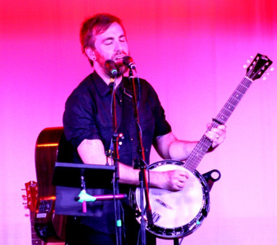 A man playing a banjo and singing into a microphone