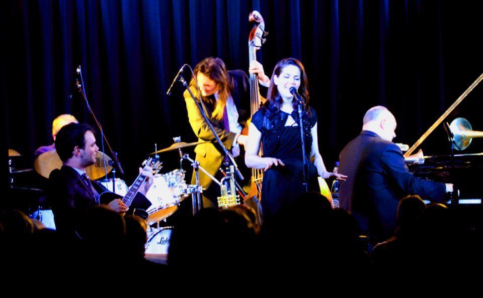 A group of people are playing instruments on a stage in front of a crowd.