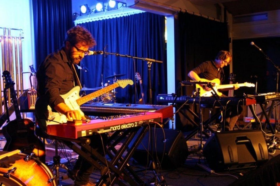 A man is playing a keyboard while another man sings into a microphone