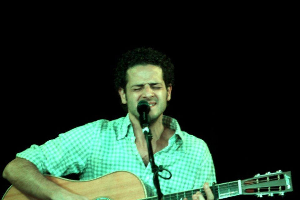 A man singing into a microphone while holding a guitar