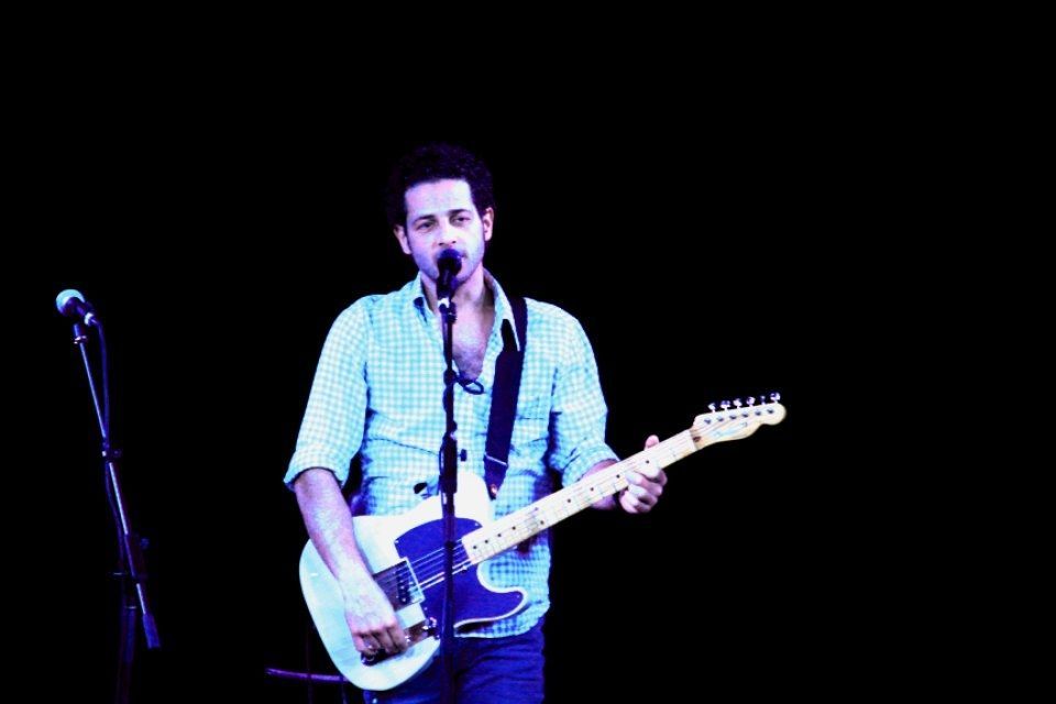 A man is playing a guitar and singing into a microphone.