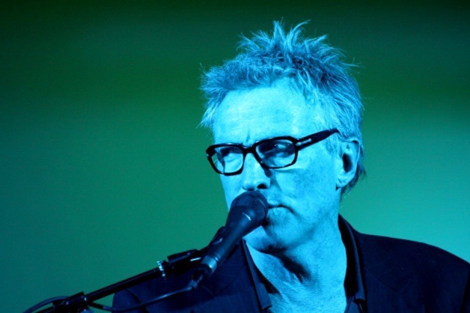 A man wearing glasses is singing into a microphone.