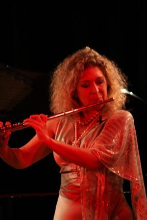 A woman is playing a flute in a dark room