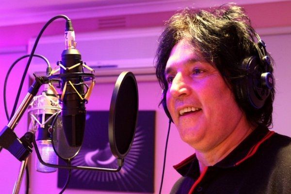 A man wearing headphones is singing into a microphone