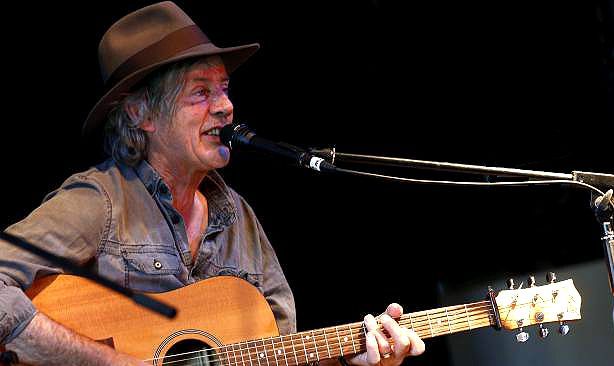 A man in a hat is playing a guitar and singing into a microphone.