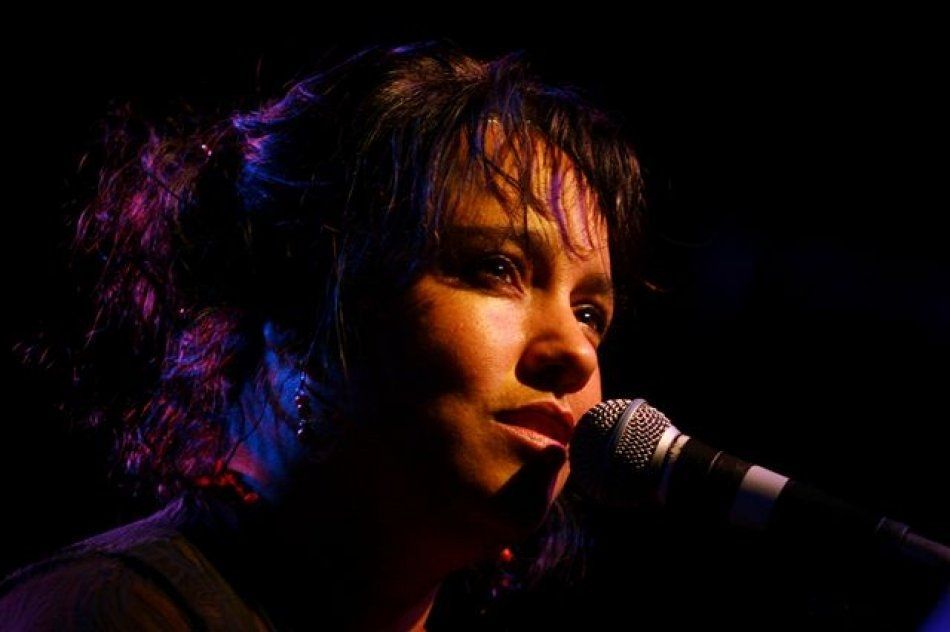 A woman is singing into a microphone in a dark room.