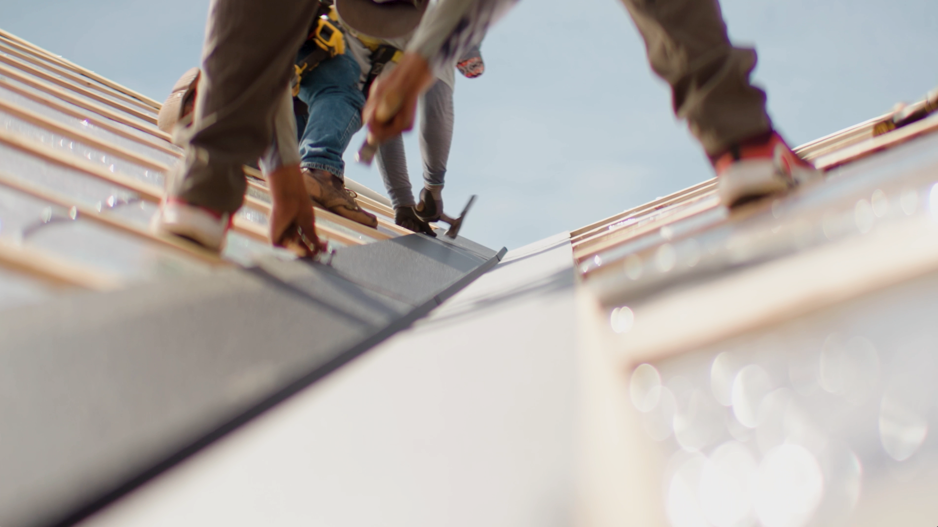 Construction workers installing roof shingles on a sunny day.