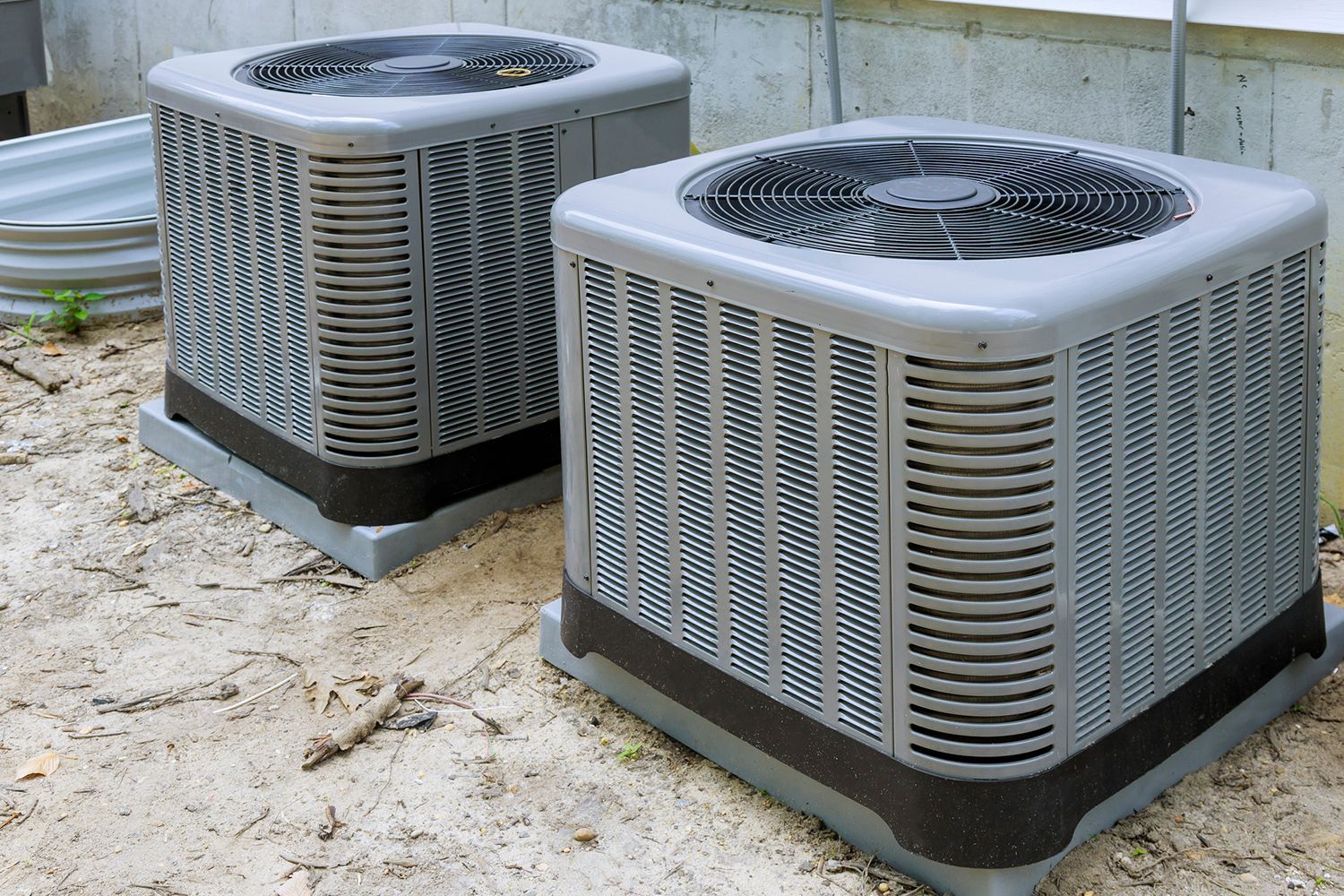 Two gray air conditioning units outdoors.