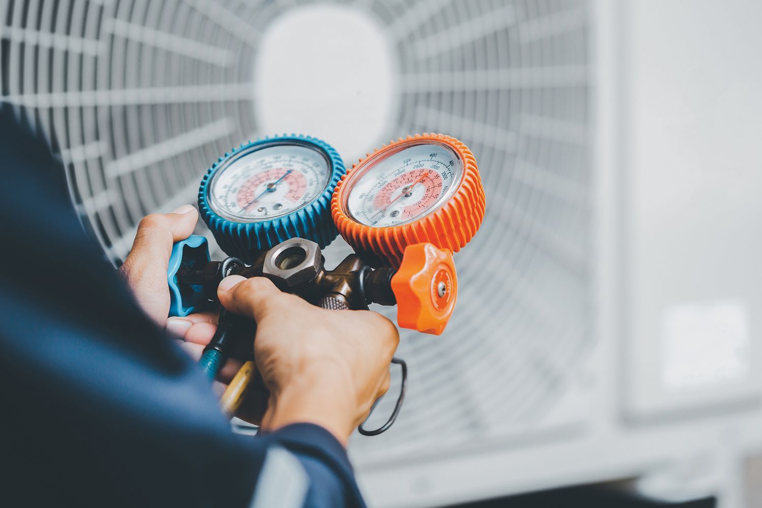 HVAC technician repairs an air conditioning unit outside a house.