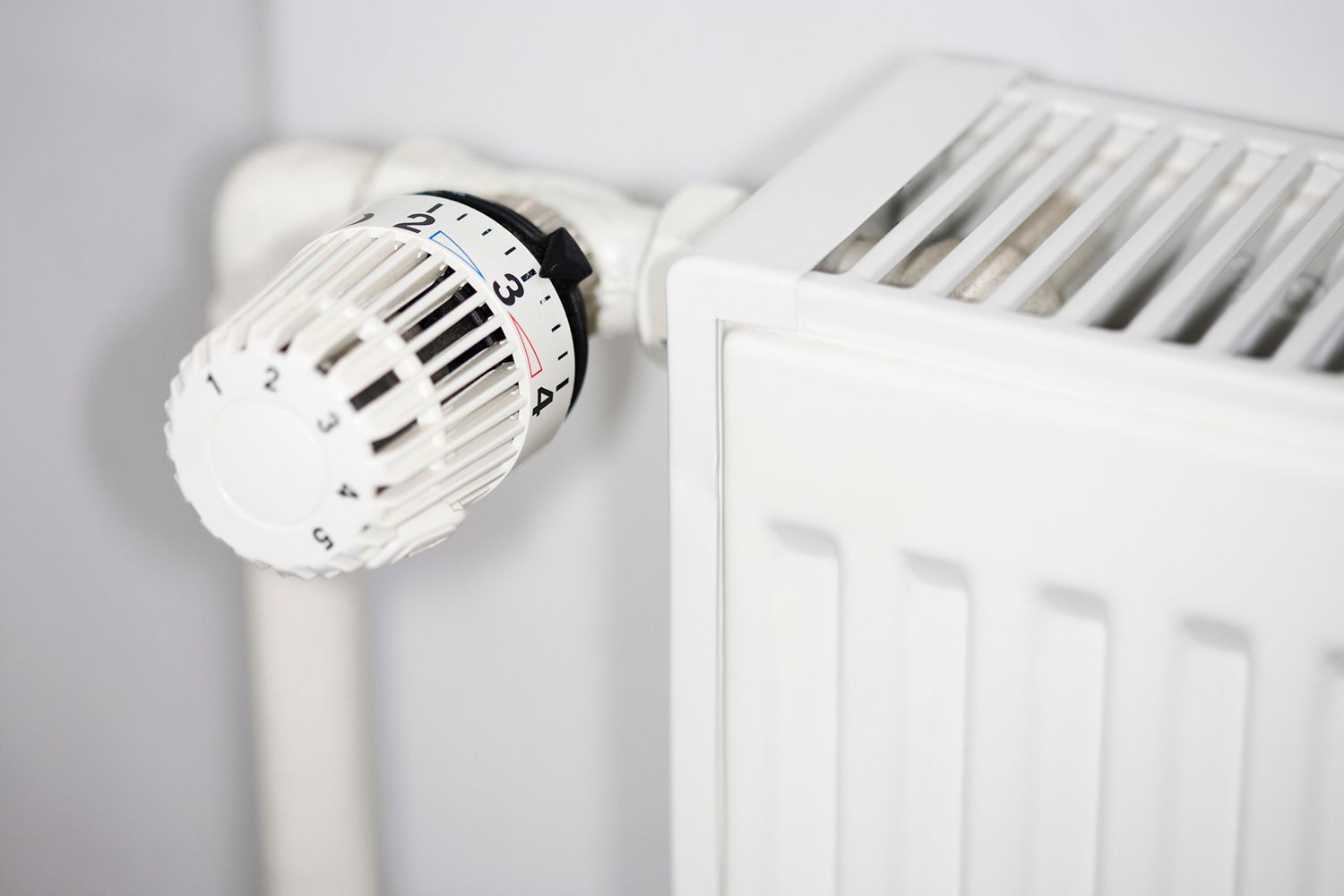 White radiator with a thermostat, mounted on a wall.