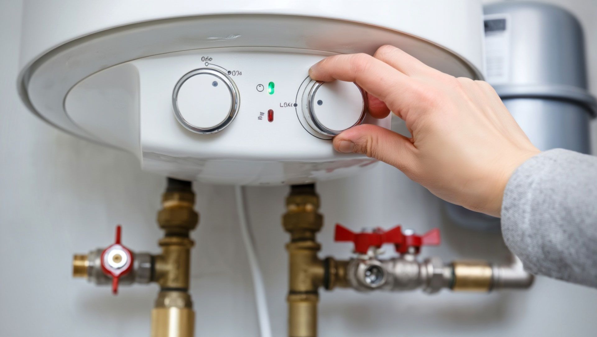 A hand adjusting a dial on a white water heater, close-up with pipes.