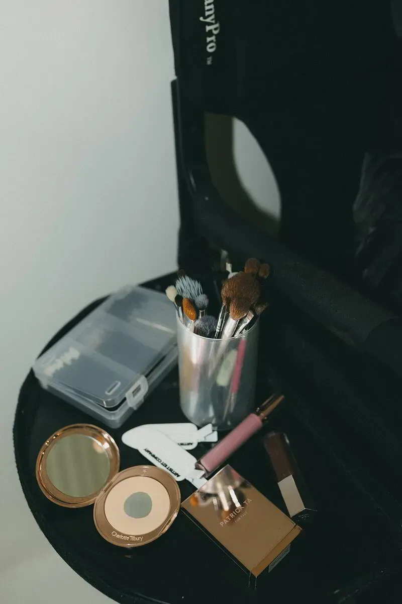 Open makeup case filled with various cosmetic products, including foundations, powders, and lip products.