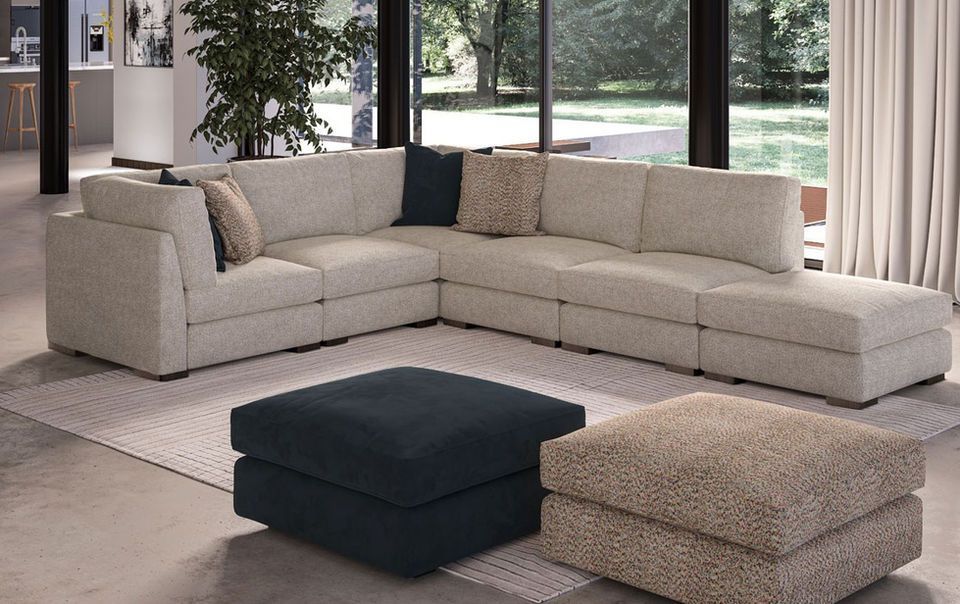 A living room with a large sectional couch and two ottomans