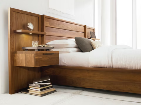Wooden bed frame with attached nightstand, books, clock, and tablet, in a bright room.