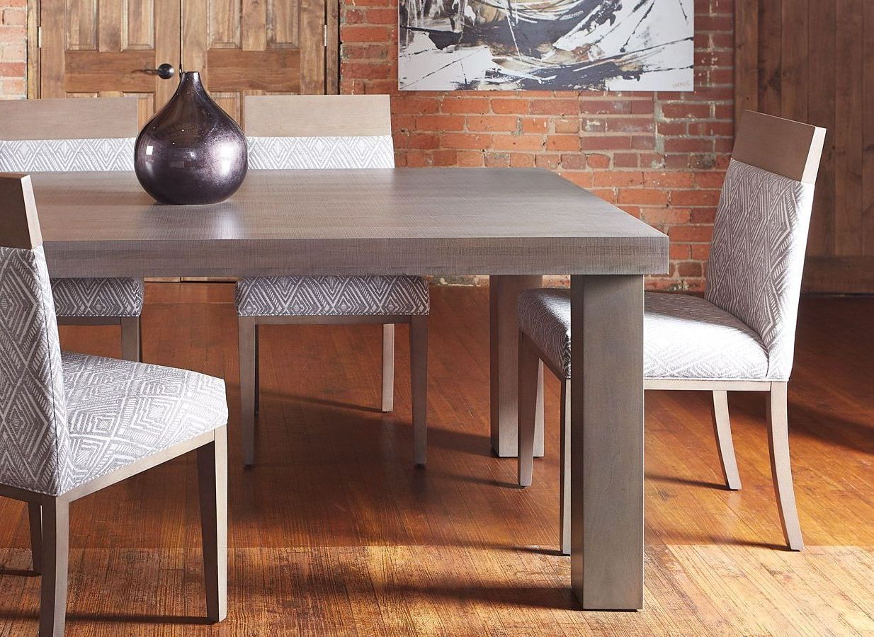 A dining room table with chairs and a vase on it
