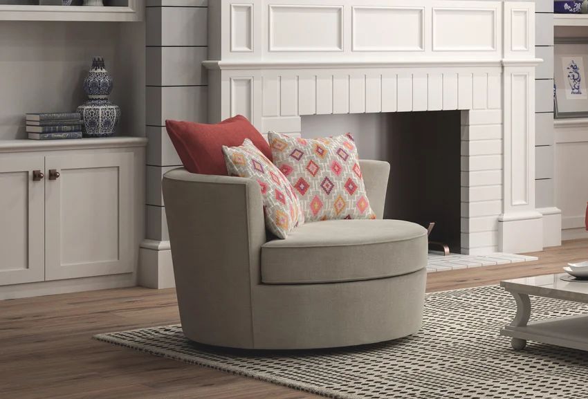 A beige swivel chair with red and patterned pillows