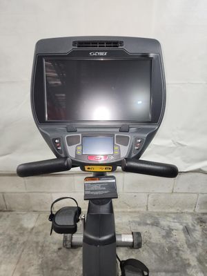 A black exercise bike with a large screen is sitting on a concrete floor.