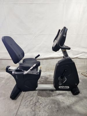 A black recumbent exercise bike is sitting on a concrete floor.