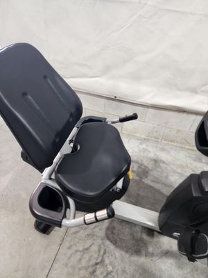 A black recumbent exercise bike is sitting on a concrete floor.
